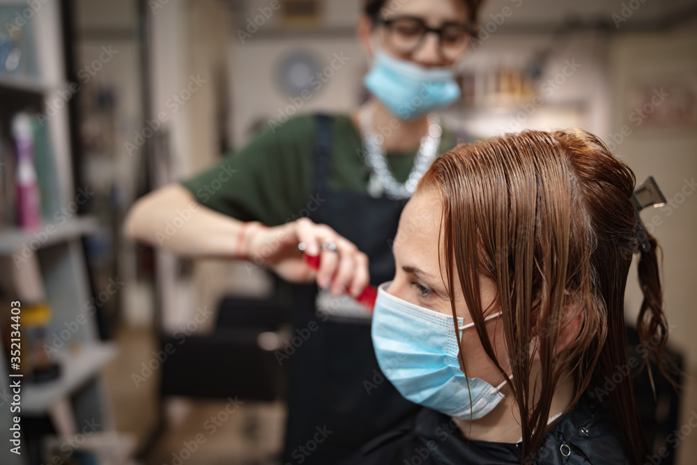 Hairdresser and customer in a salon with medical masks during virus pandemic. Working with safety mask. Hairdresser and customer in a salon with medical masks during virus pandemic. Working with safety mask.