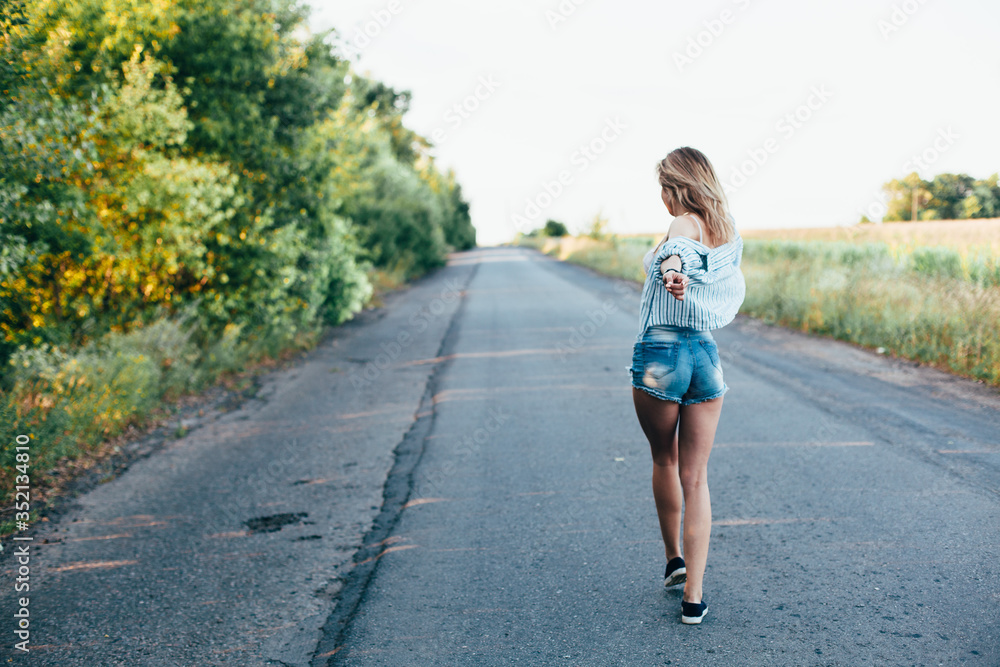 Beautiful girl hitchhiking on the track in a man's shirt Beautiful girl hitchhiking on the track in a man's shirt