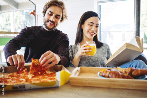 Happy family couple have pizza break for lunch together in the middle of remote working day