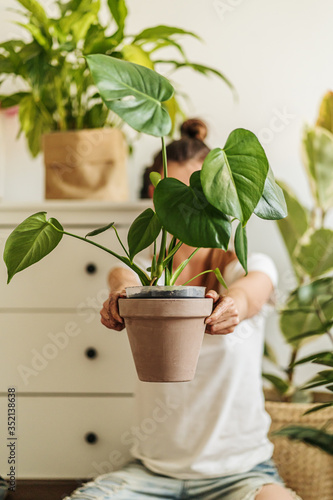 Slika na platnu Young woman transplanting plant in ceramic pots on the floor