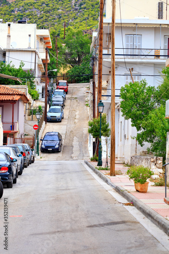 The deserted old narrow street of Loutraki in Greece, the cracked surface of the roadway, rises uphill.