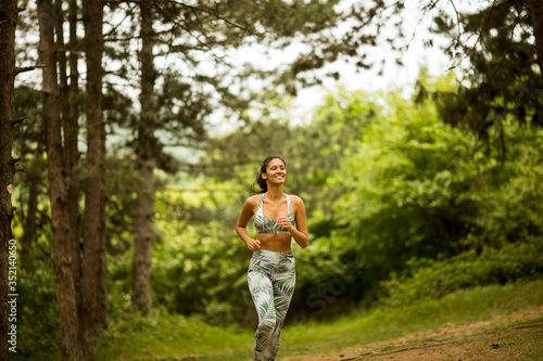 Young fitness woman running at forest trail