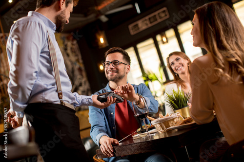 Young man paying with contactless credit card in restaurant after dinner