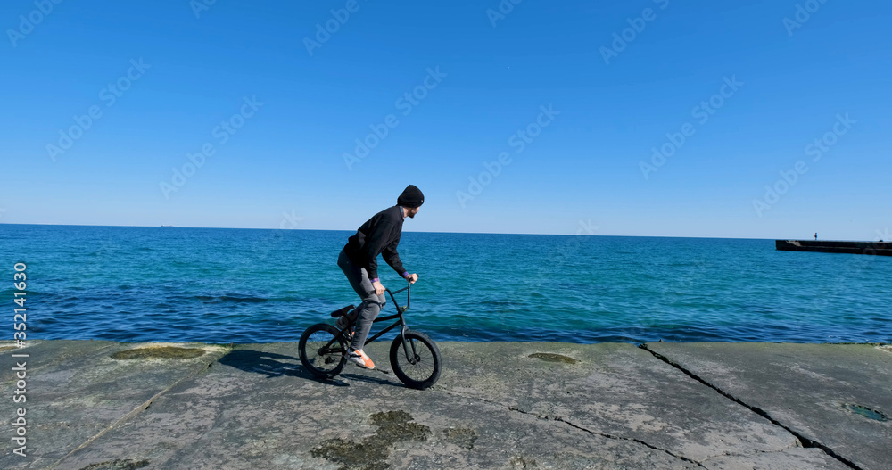 Fototapeta premium Young male with bmx bicycle ride near the sea