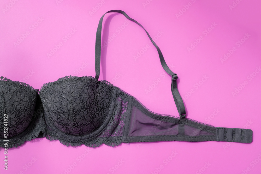Gray bra on a pink background top view. Fragment of a lace bra with a fastener and straps. Beautiful sexy lingerie, concept of female sexuality, breast health. Gray bra on a pink background top view. Fragment of a lace bra with a fastener and straps. Beautiful sexy lingerie, concept of female sexuality, breast health.