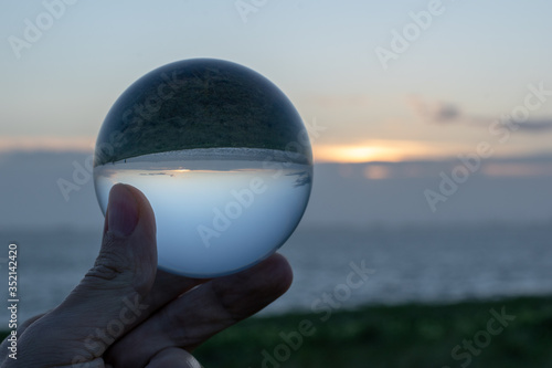 Sunset over the sea seen through a glasball