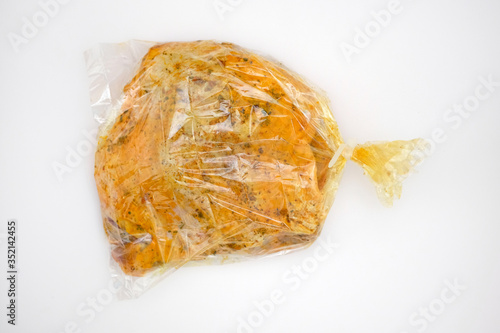 Spiced meat in a transparent baking bag. Raw turkey thigh in a baking sleeve on a white background. Baking meat without contaminating dishes.