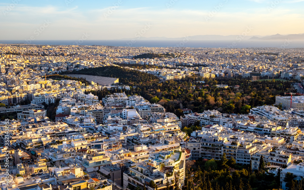 Panoramic sunset view of Athens, Greece, with Panathenaic Stadium, and Piraeus at Saronic Gulf of Aegean sea in background seen from Lycabettus hill