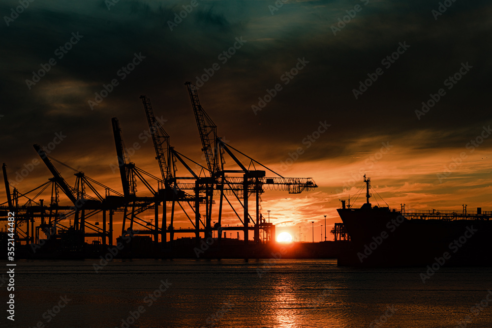 A large ship and container cranes at sunset