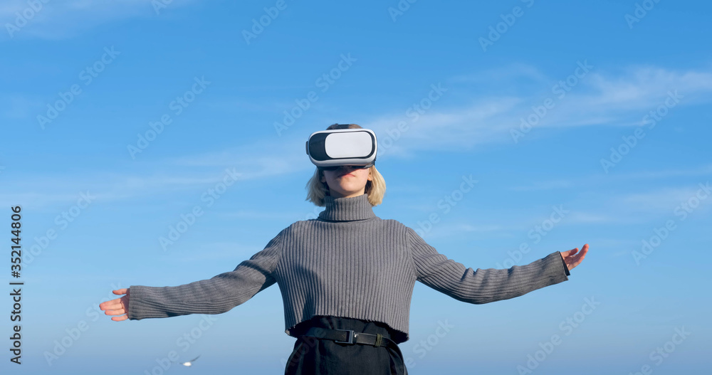 Young handsome female with virtual reality glasses outdoor on the beach against sunny blue sky Young handsome female with virtual reality glasses outdoor on the beach against sunny blue sky