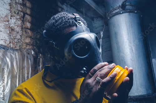 Fototapeta Naklejka Na Ścianę i Meble -  A black male with a military grade gas mask to protect himself from the corona virus covid19. Face mask used to prevent the spread of the virus. Mandatory face coverings.