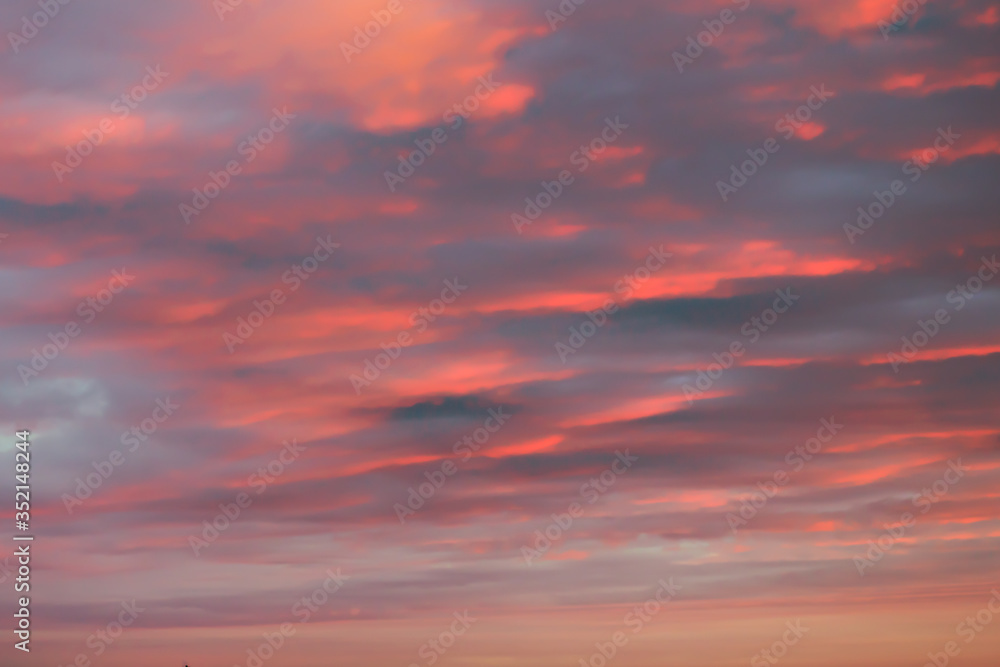 Dreamy romantic sky with clouds at sunset in orange.