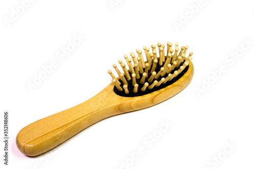 Small yellow wooden massage comb rests on a white background