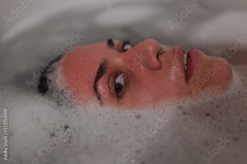 Mujer sumergida en la bañera mirando a camara