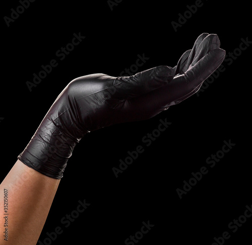 Hand in black glove holding something isolated on black background