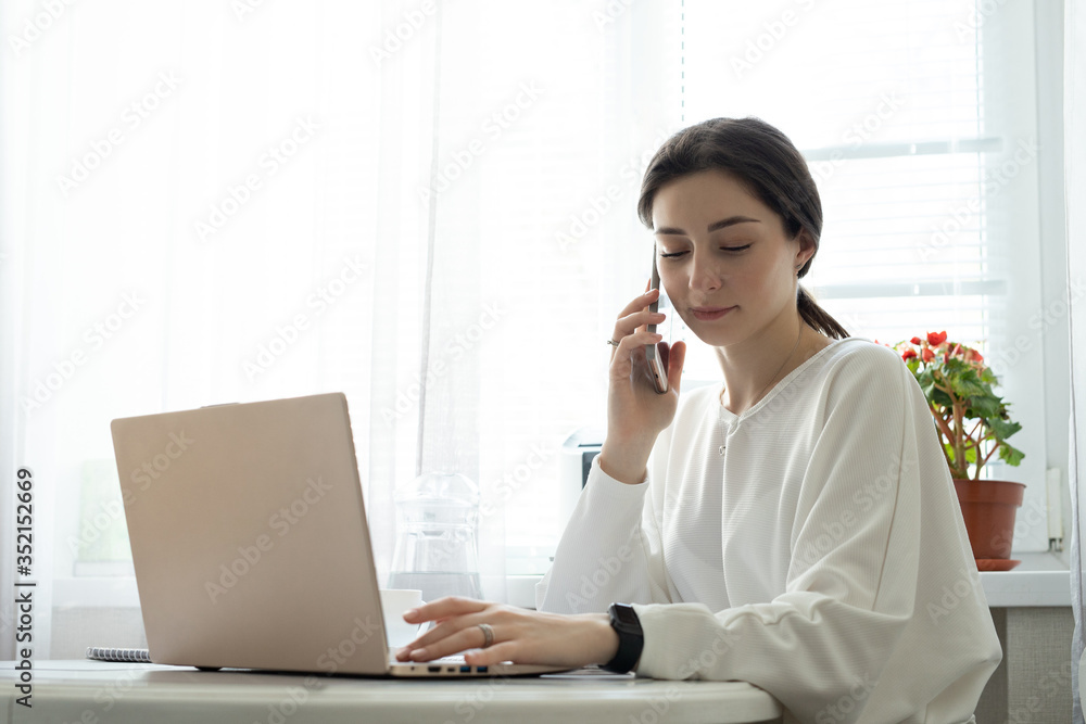 Smiling freelancer consults by cell phone at home Smiling freelancer consults by cell phone at home
