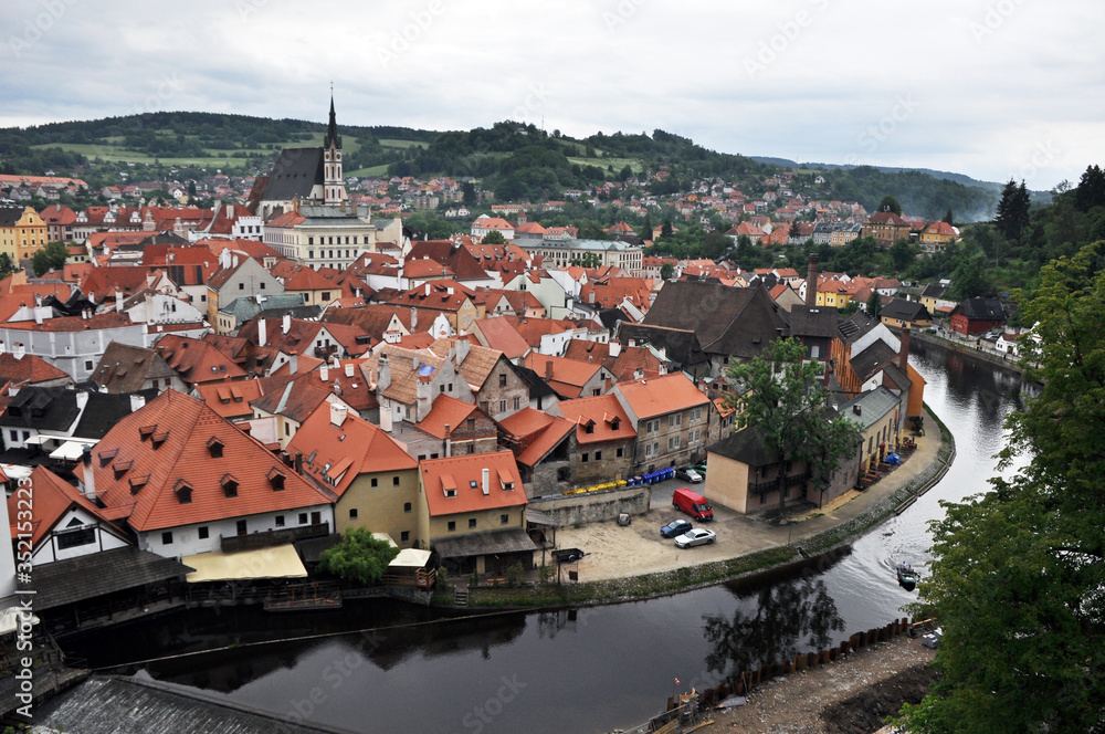 Summer panorama from the castle fortress wall to the Vltava embankment and the tiled roofs of the houses of the historic part of Cesky Krumlov
