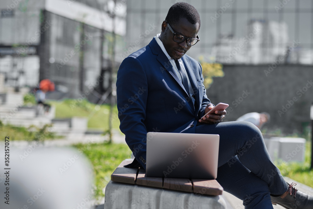 African man working on laptop and smart phone outdoor African man working on laptop and smart phone outdoor