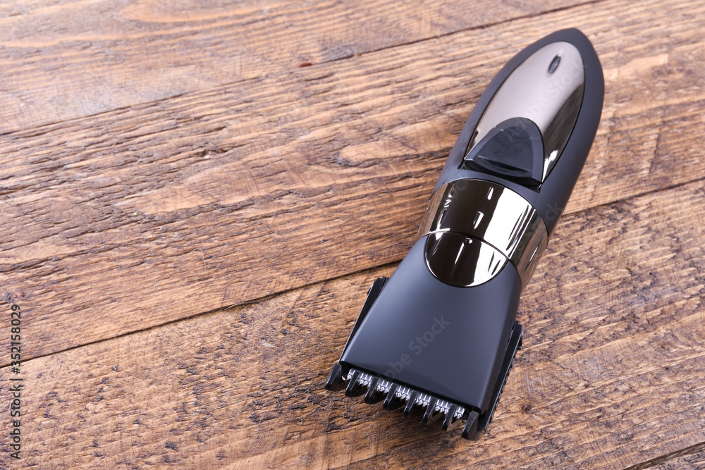 Trimmer with nozzles. Buying a new wireless trimmer. On a wooden background. Close-up. With space for text Trimmer with nozzles. Buying a new wireless trimmer. On a wooden background. Close-up. With space for text
