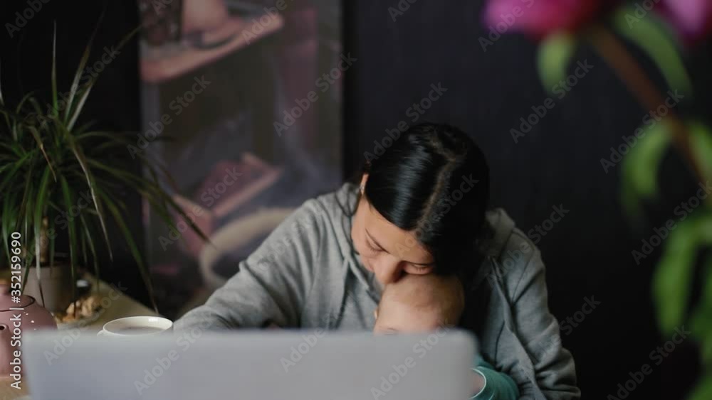 Young mother with a 6 month old baby in her arms works on a laptop while sitting at a table in the kitchen. in slow motion Young mother with a 6 month old baby in her arms works on a laptop while sitting at a table in the kitchen. in slow motion
