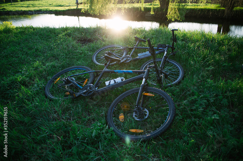 Two sports bikes on the grass near the river in the sunset sunlight