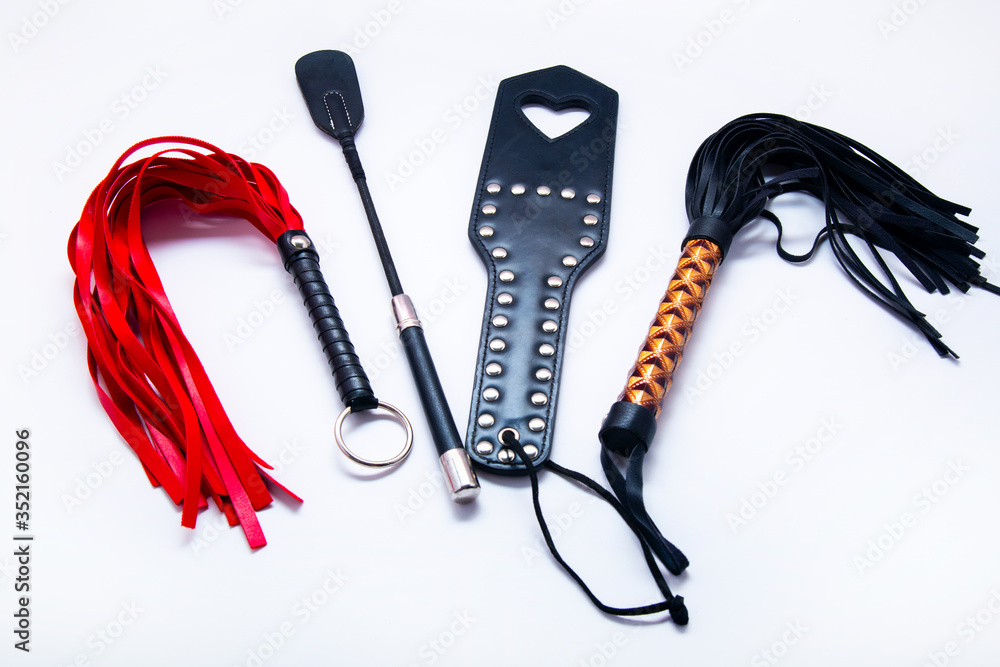 Whip on white background. Accessories for adult sexual games. Toys for  BDSM, spanking devices. Spanking and punishment concept. Slave Spank  Paddle, bdsm, adult whips. copy space. Set for bdsm Stock Photo