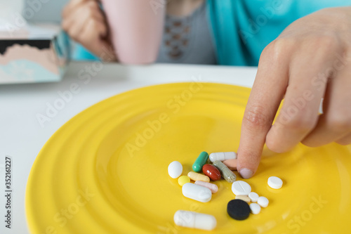 On the plate lies a set of tablets and vitamins as well as antibiotics that are necessary during every illness and cold.