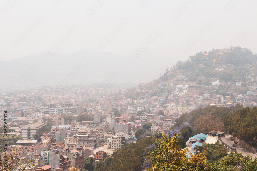 Cityscape of Kathmandu city in Nepal. Smog covers the sky. Most of buildings made from red bricks. Residential architecture theme. View from Swayambhunath Stupa. Selective focus.