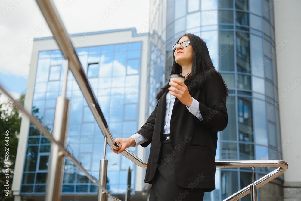 Portrait of successful business woman going to work with coffee walking near office building on city street. Portrait of successful business woman going to work with coffee walking near office building on city street.