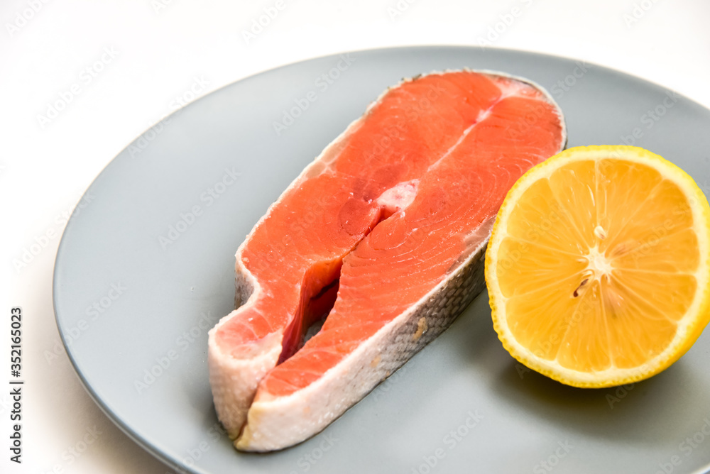 Close up fresh raw salmon steak with lemon slice isolated on white background