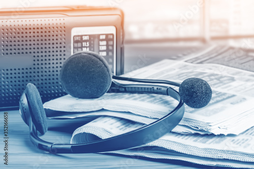 Radio, headphones with a microphone and newspapers on the office desk, media latest news concept.