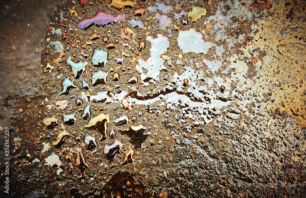 Oil stain on Asphalt road after rain. Multi-colored poisonous spots on the parking. Oil stain on Asphalt road after rain. Multi-colored poisonous spots on the parking.