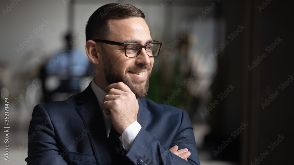 Smiling businessman wearing glasses dreaming about good future close up, touching chin, business vision concept, team leader standing in modern office, looking in distance, thinking about project - obrazy, fototapety, plakaty 
