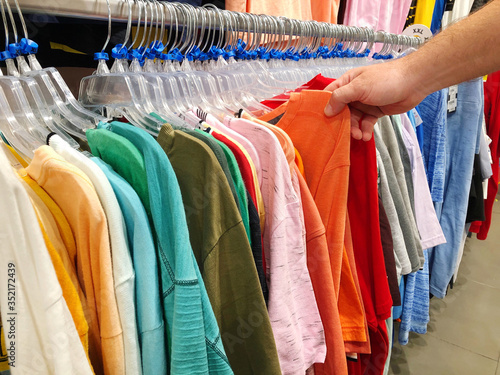 Men's hand pulling out clothing from the rack