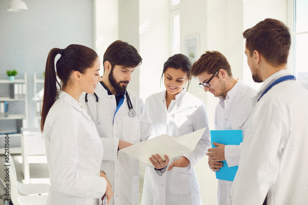 A team of doctors in a meeting discusses the diagnosis of a patient in a clinic office.