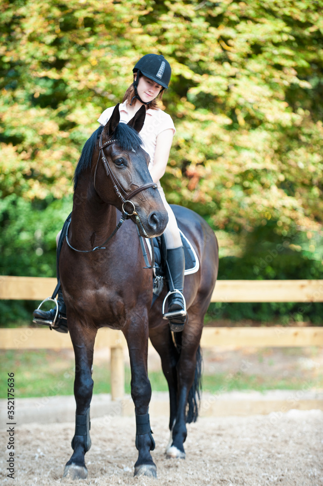Young girl riding horseback at early morning in sunlight Young girl riding horseback at early morning in sunlight