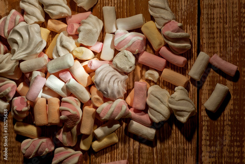Lots of sweets on a wooden table. Pink with orange marshmallows and bize close up. Candy on a shabby old board.