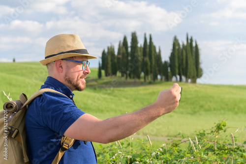 Young beautiful man Hiking in Tuscany and Italian medieval towns with a backpack