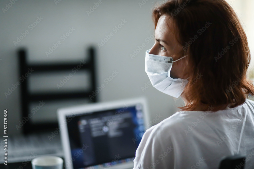 a woman in a mask and gloves works on a laptop, a doctor during the pandemic a woman in a mask and gloves works on a laptop, a doctor during the pandemic