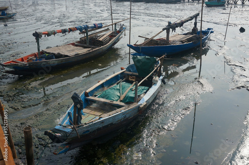 Wooden, Indonesian small boats in the inner harbor at low tide. Gresik, Indonesia. © aerrant