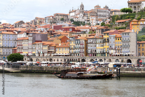 Porto, Portugal - 23 June, 2019: Traditional boats anchored on the Douro River with the Cais da Ribeira in the background, in the city of Porto, Portugal