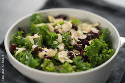 Salad with kale, cranberries and almond flakes in white bowl on linen napkin