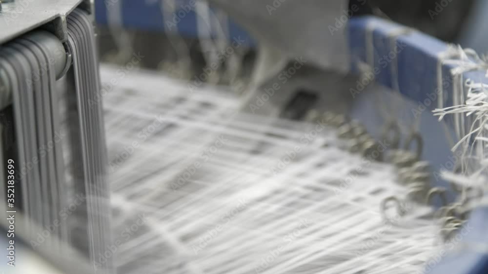 Modern machine with rushing plastic strings producing agricultural bags at a plant Modern machine with rushing plastic strings producing agricultural bags at a plant