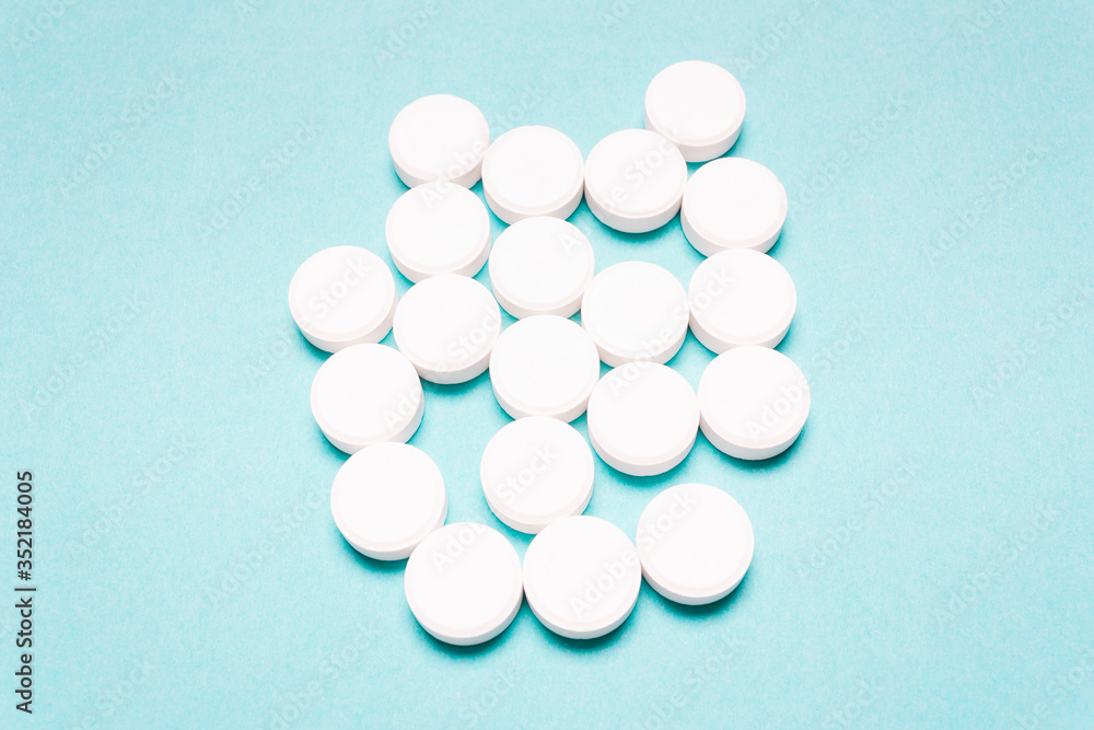 Round, white pills on a blue background. Round, white pills on a blue background.