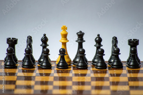 White kings surrounded by black chess pieces on chessboard