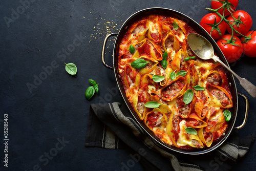 Stuffed pasta cannelloni with minced meat baked in tomato sauce in a skillet. Top view with copy space.