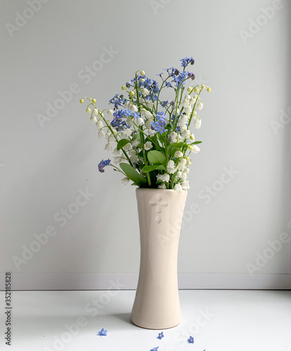 Spring bouquet of lilies of the valley and blue flowers on a white background in a vase. Spring flowers. A gift for your loved ones.