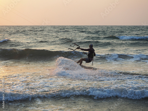 India, Goa, Arambol, a man kitesurfing near the coast at sunset