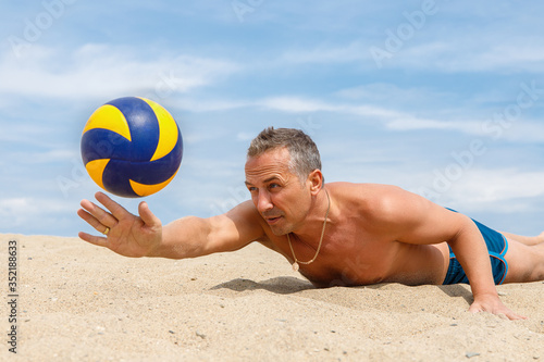 young man playing volleyball on the beach