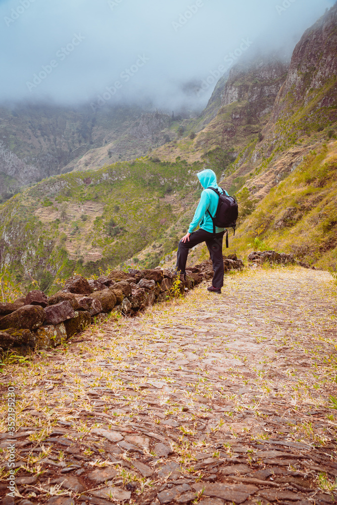Fototapeta premium Active vacation tourism. Man enjoying impressive mountainscape. Arid canyon valley extend far below. Santo Antao, Cabo Verde